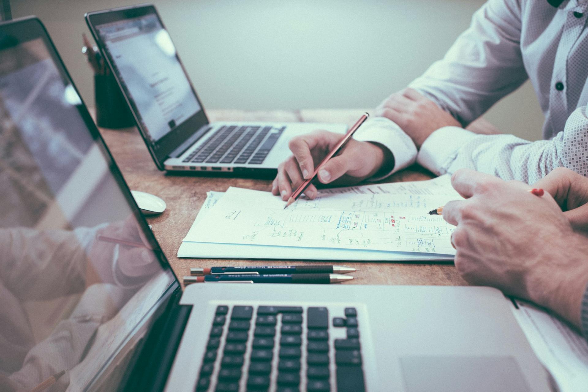 Plan technique annoté sur une table de travail, crayons et ordinateurs
